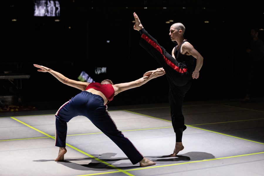 A dancer bending backwards while another kicks above.