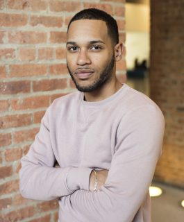 A headshot of Orlando Pazol Mendoza standing with his arms crossed in a brick interior-space.