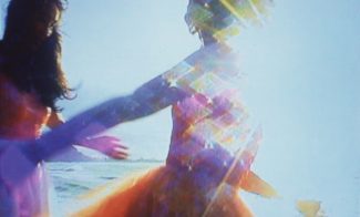 A color photograph reproduces two figures running in close-up over a brightly sunlit beach, the image abstracted by colorful solar flare.
