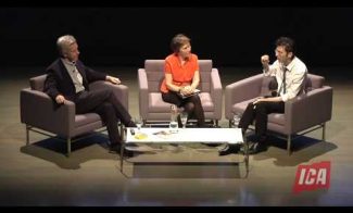 Three people are seated on stage in a conversation, with two men and one woman. They are sitting on chairs around a small table, with the ICA logo visible in the bottom right corner. The background is dark.